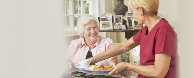 caregiver serving food to senior woman