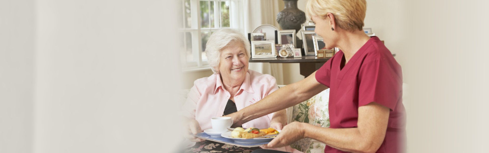 caregiver serving food to senior woman