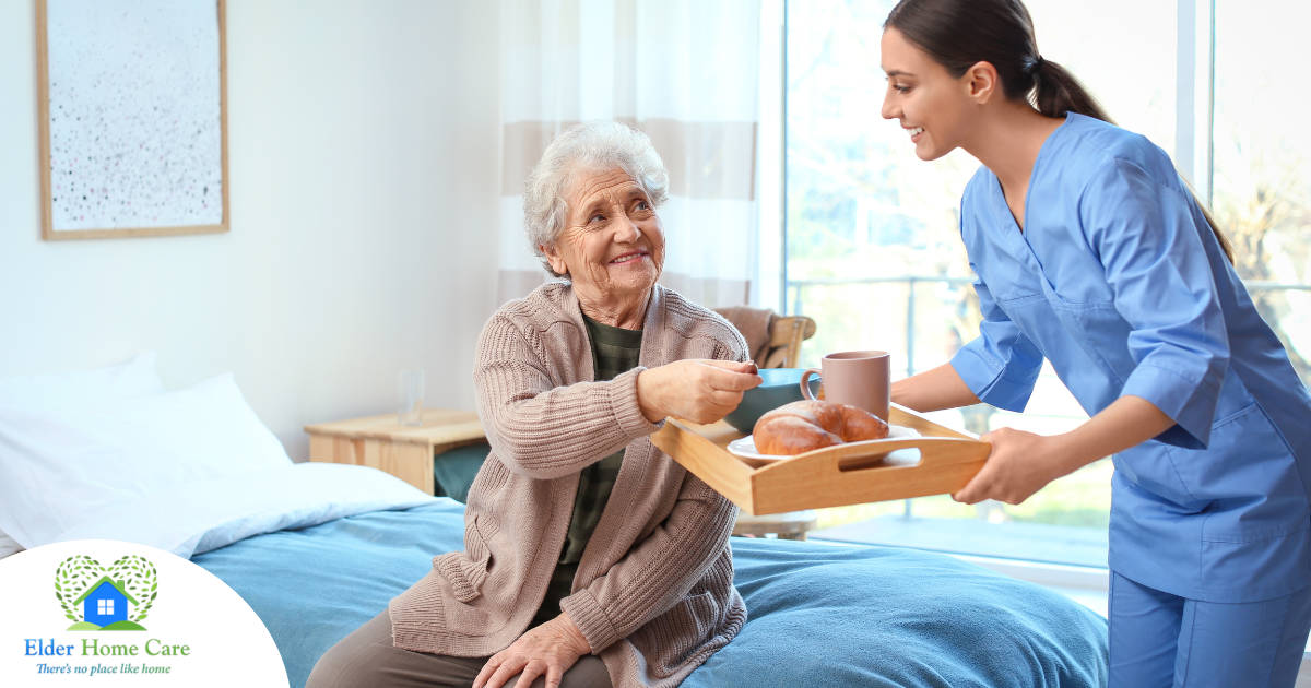 A professional caregiver smiles and provides food to an older adult in her care, representing the compassionate care needed for those with dementia.